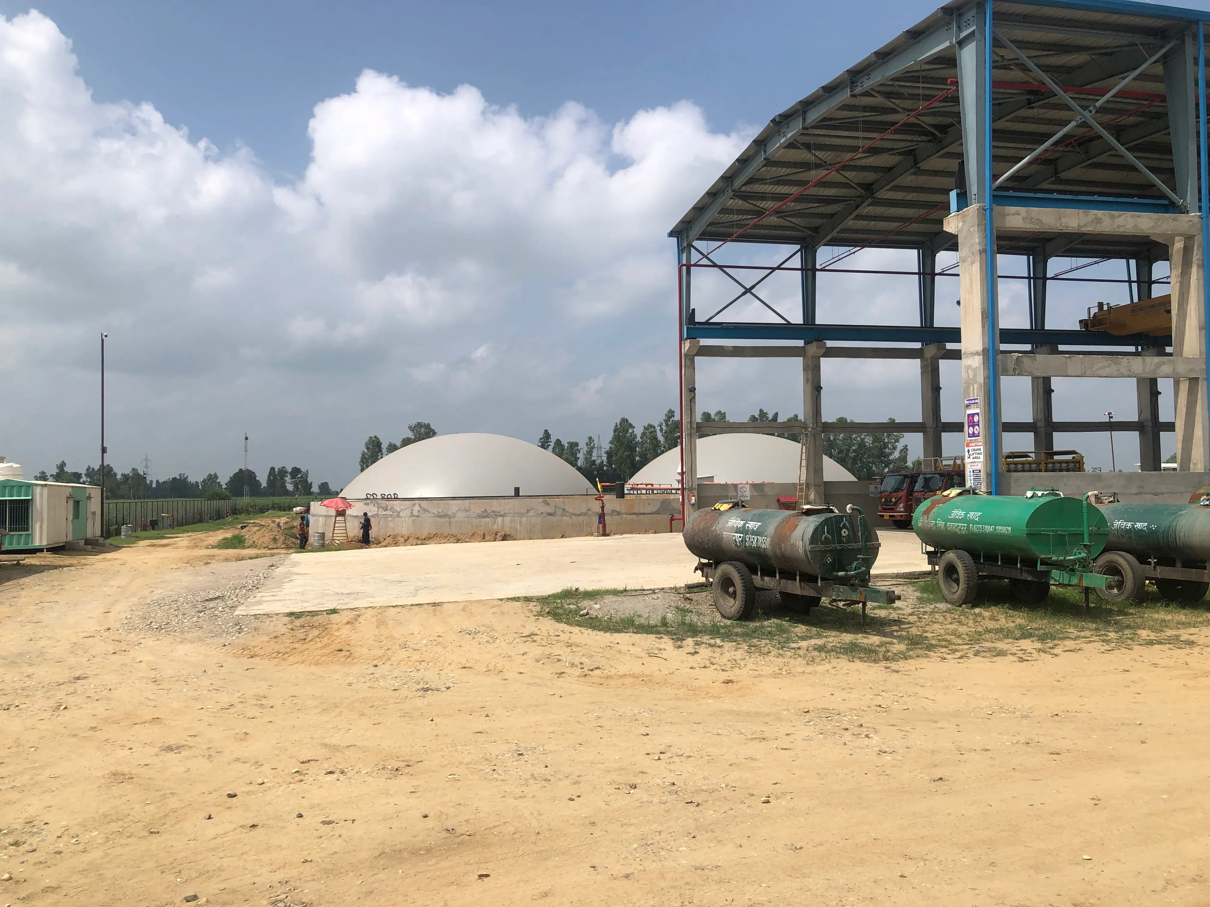 Anaerobic digesters and feedstock-slurry tankers at the Meerut compressed-biogas plant