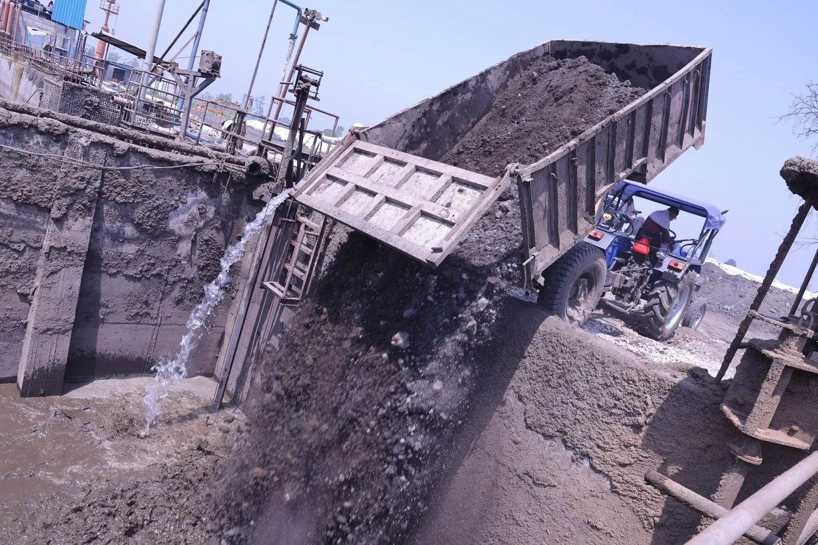 Tractor-trailer tipping sugar-mill pressmud into the receiving pit at the Meerut plant