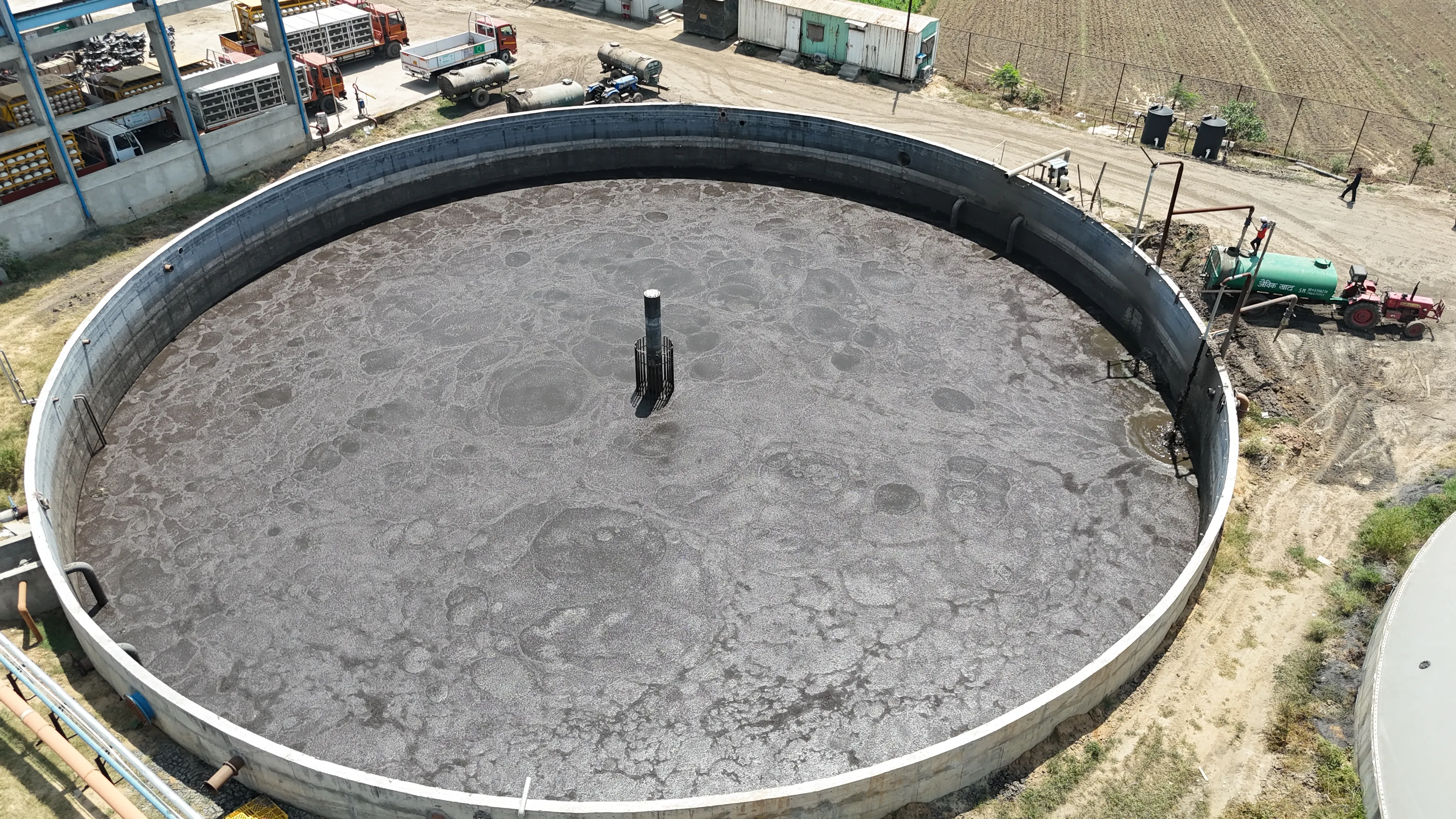 Overhead view of an open digestate tank with cracked surface at the Circle CBG Meerut plant